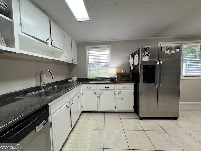 kitchen featuring stainless steel appliances, a sink, light tile patterned floors, white cabinetry, and dark countertops