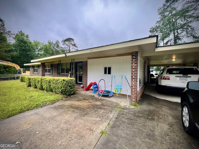 view of front of property featuring brick siding, a front lawn, concrete driveway, and a carport