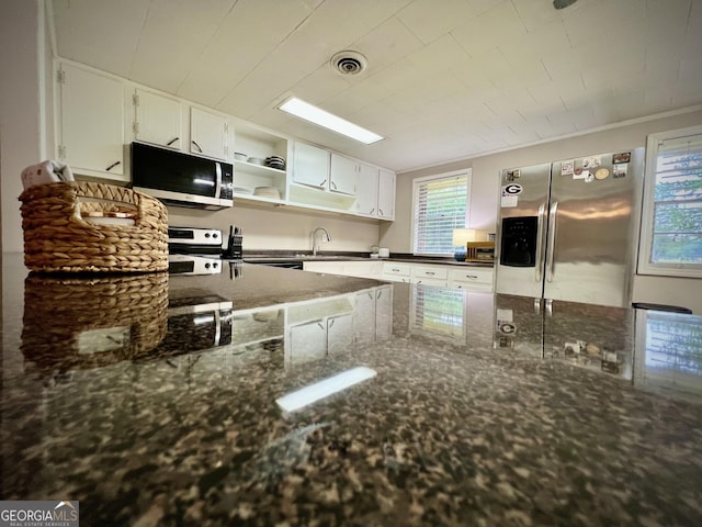 kitchen featuring appliances with stainless steel finishes, white cabinetry, a sink, dark stone countertops, and open shelves