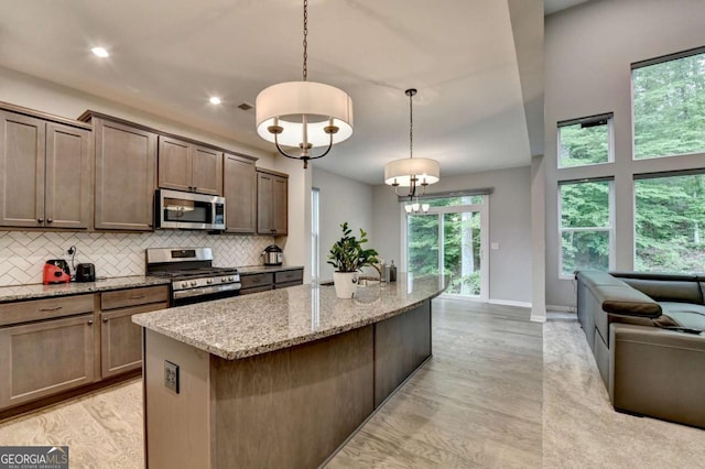 kitchen with stainless steel appliances, decorative backsplash, light stone counters, light wood finished floors, and recessed lighting
