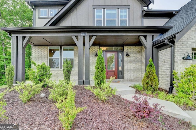 doorway to property with brick siding, board and batten siding, and covered porch