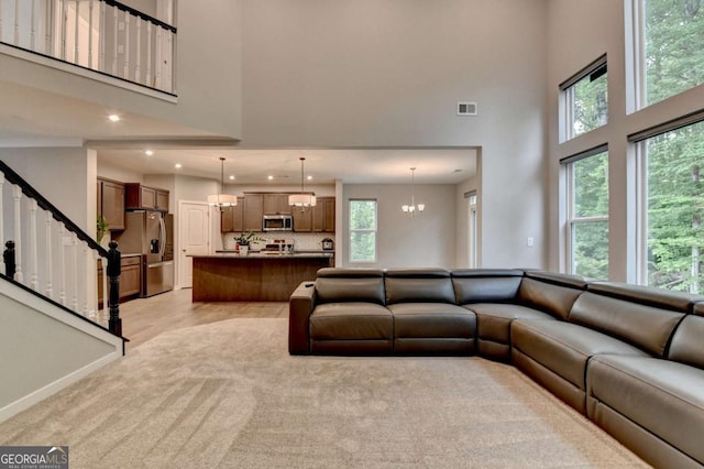 living room featuring a high ceiling, a chandelier, recessed lighting, stairway, and baseboards