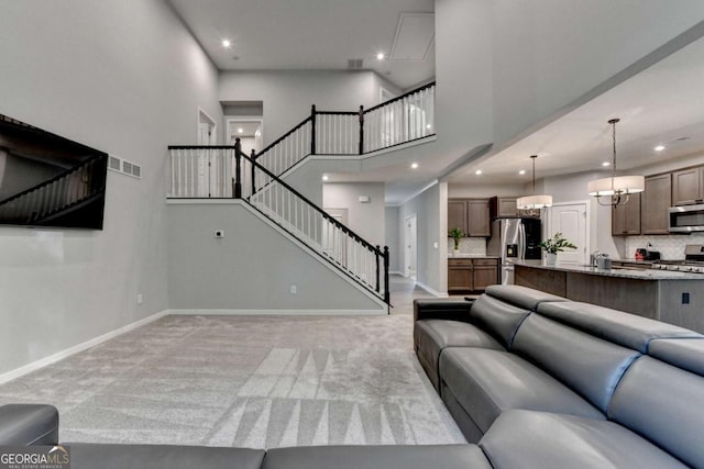 living area with light colored carpet, stairs, baseboards, recessed lighting, and a towering ceiling