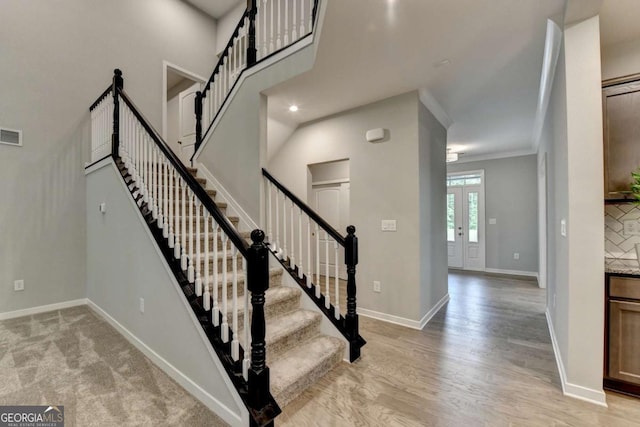 stairway featuring baseboards, wood finished floors, and crown molding
