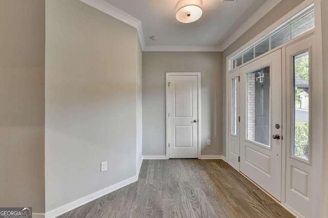 entryway with wood finished floors, baseboards, and ornamental molding