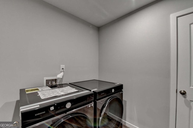 laundry room with washer and dryer, baseboards, and wood finished floors
