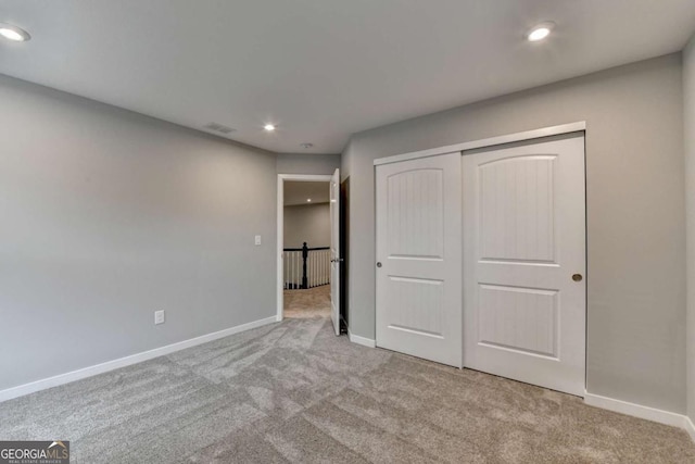 unfurnished bedroom with carpet floors, recessed lighting, baseboards, and a closet