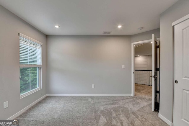 empty room with healthy amount of natural light, light colored carpet, baseboards, and recessed lighting