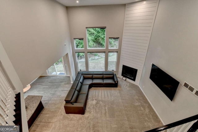 living area with a large fireplace, baseboards, recessed lighting, and a high ceiling