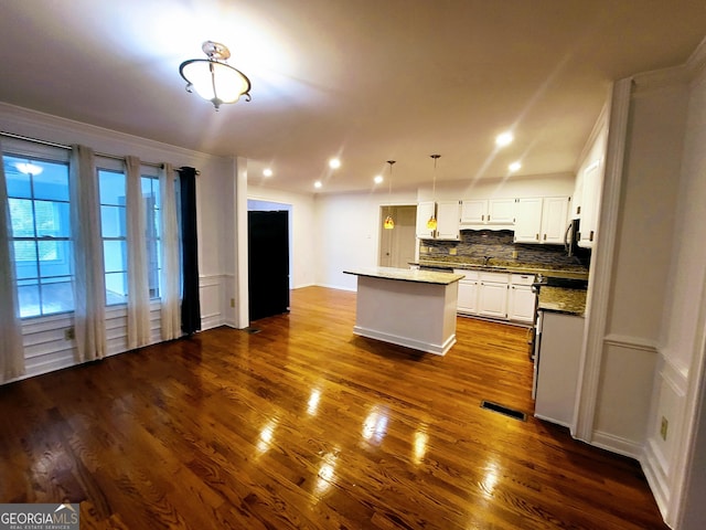 kitchen featuring a center island, dark wood-style floors, decorative backsplash, white cabinets, and a sink