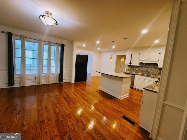 kitchen with a center island, dark wood finished floors, white cabinetry, decorative backsplash, and dishwasher