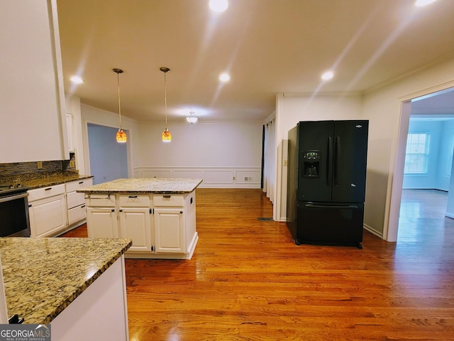 kitchen with black fridge, white cabinets, wood finished floors, stainless steel electric range, and stone countertops