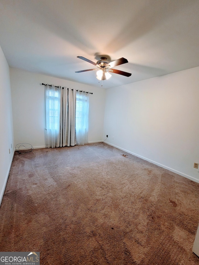 spare room with a ceiling fan, carpet floors, and baseboards