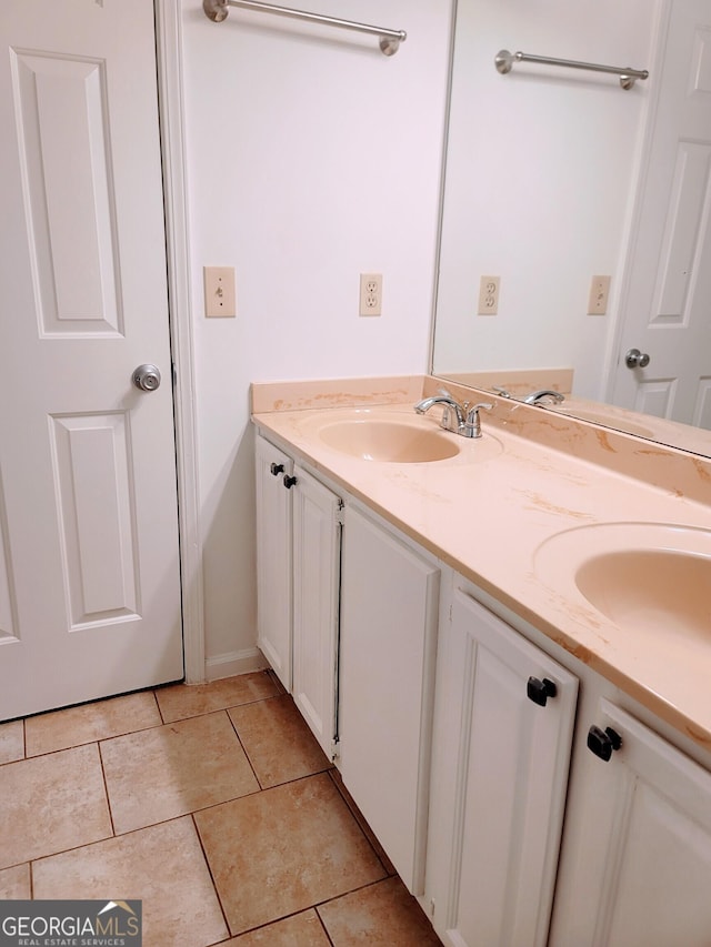 full bath featuring double vanity, tile patterned floors, and baseboards