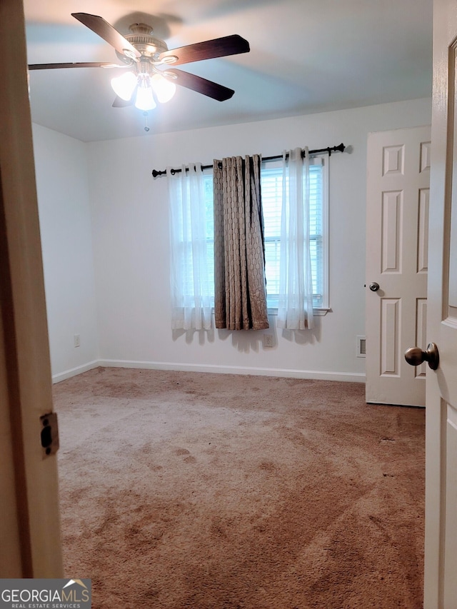 spare room with carpet floors, a ceiling fan, and baseboards