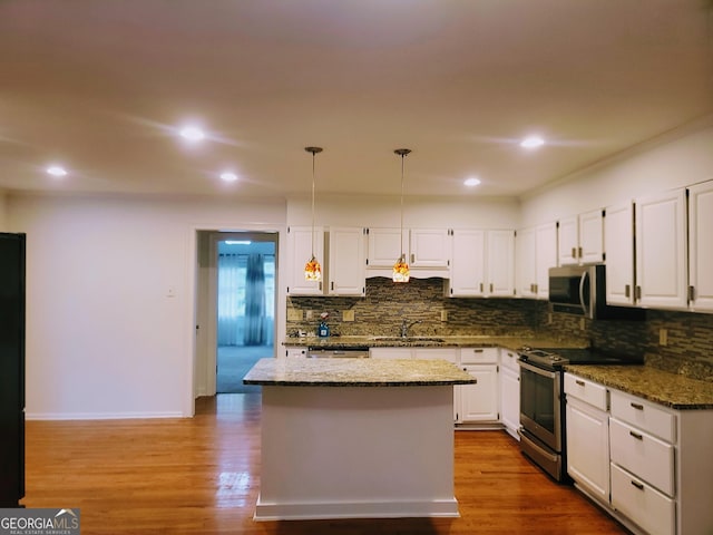 kitchen featuring appliances with stainless steel finishes, a sink, decorative backsplash, white cabinets, and recessed lighting