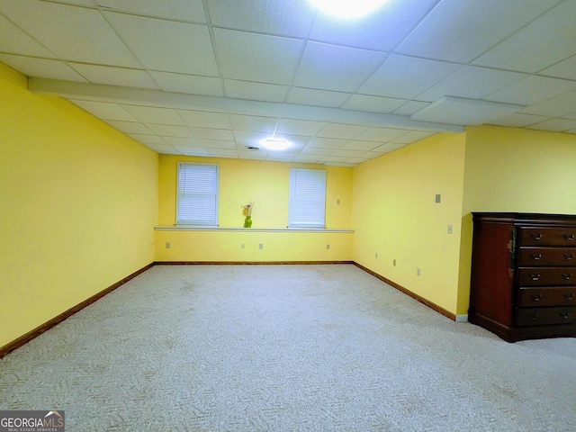 below grade area featuring carpet flooring, baseboards, and a paneled ceiling