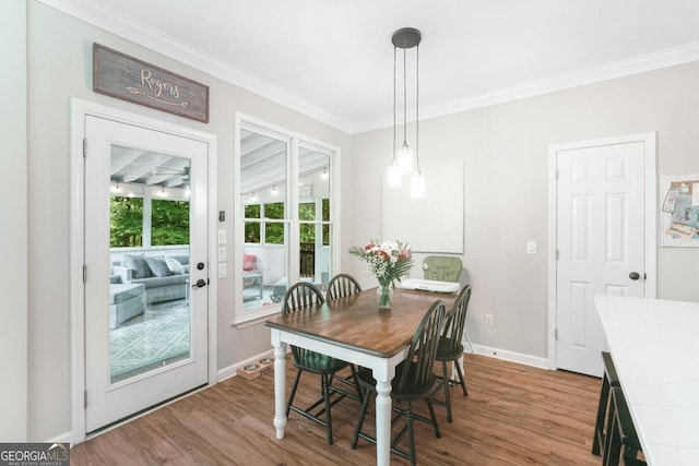 dining room with wood finished floors, ornamental molding, and baseboards