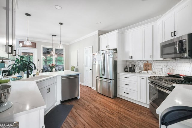 kitchen with stainless steel appliances, a sink, crown molding, decorative backsplash, and white cabinets