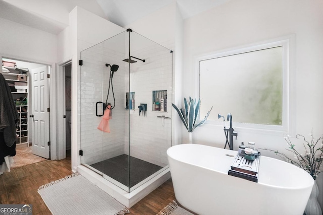 bathroom featuring a shower stall, wood finished floors, and a freestanding bath
