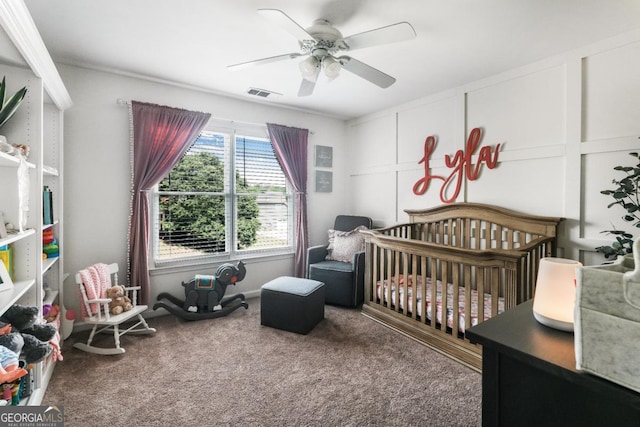 bedroom featuring a nursery area, carpet flooring, and ceiling fan