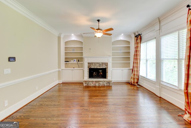 7520 Ledgewood Way, Suwanee, GA 30024 - unfurnished living room featuring a ceiling fan, a fireplace, built in features, wood finished floors, and crown molding