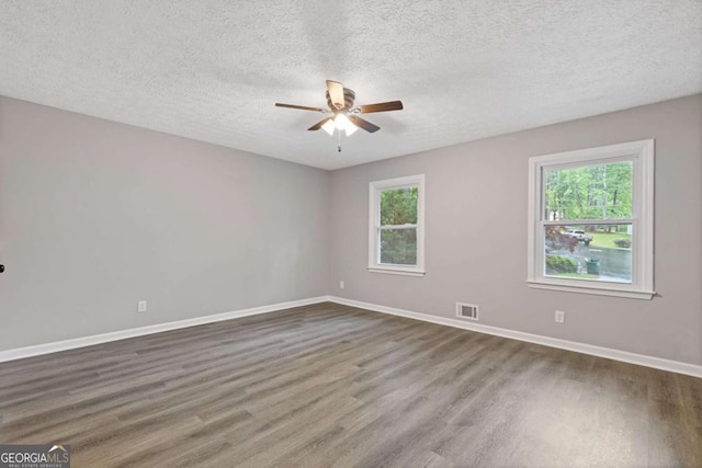 unfurnished room featuring ceiling fan, dark wood-type flooring, baseboards, and a textured ceiling