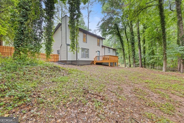 rear view of property with a deck, fence, and a chimney
