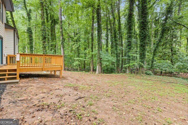 view of yard with a deck and a view of trees