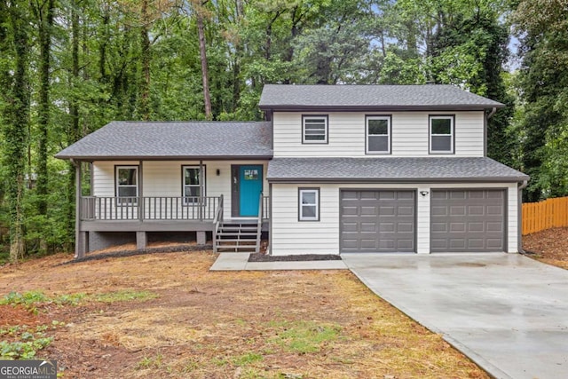 split level home with covered porch, a garage, concrete driveway, fence, and a shingled roof