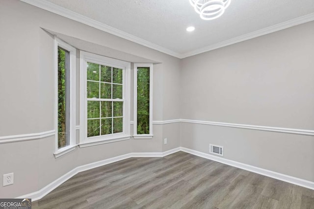 empty room with wood finished floors, baseboards, ornamental molding, a chandelier, and recessed lighting