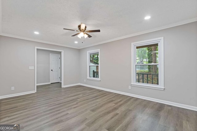 empty room featuring plenty of natural light, a ceiling fan, wood finished floors, recessed lighting, and crown molding