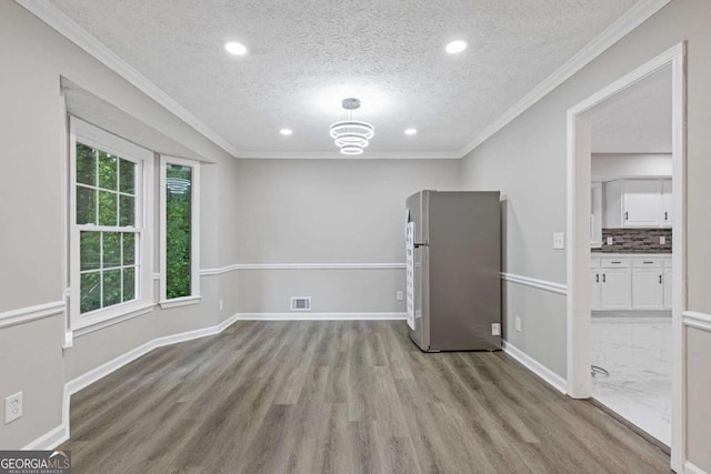 unfurnished room with a textured ceiling, wood finished floors, recessed lighting, baseboards, and ornamental molding