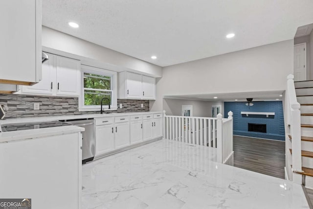kitchen featuring dishwasher, white cabinetry, recessed lighting, backsplash, and a fireplace