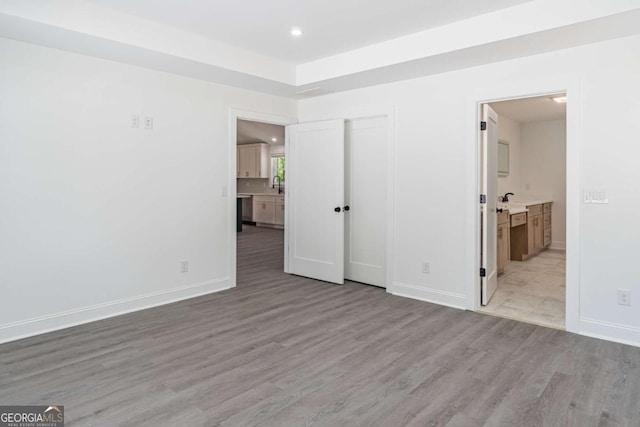 2265 Hillbriar Dr, Buford, GA 30518 - unfurnished bedroom with wood finished floors, recessed lighting, baseboards, connected bathroom, and a sink