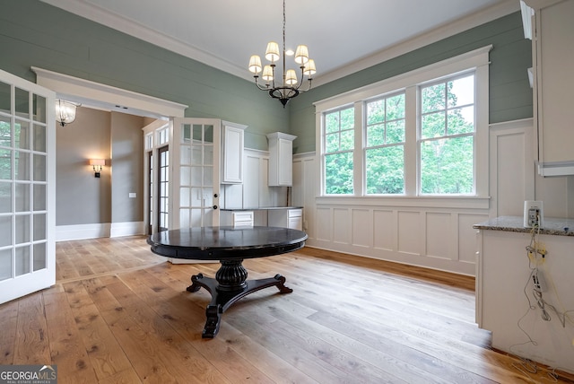 dining space with a chandelier, light wood finished floors, and a decorative wall