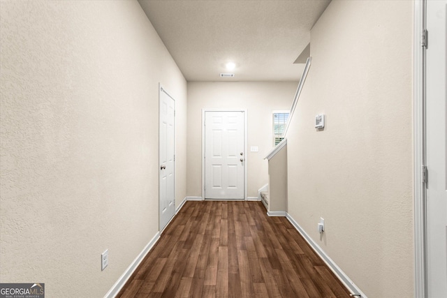 hall with dark wood-style floors, baseboards, and stairway
