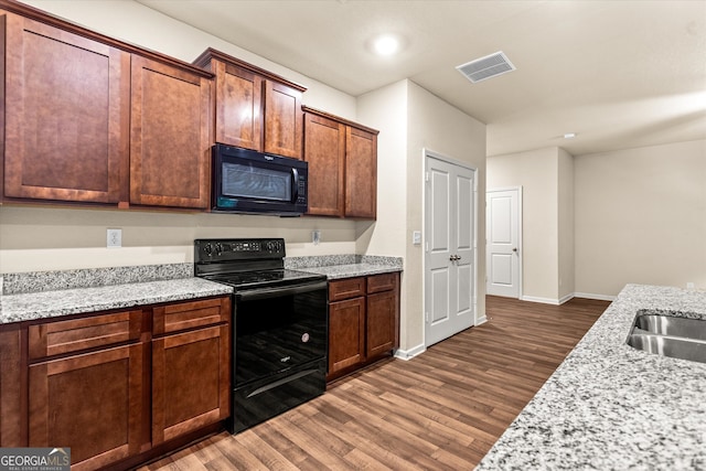 kitchen featuring black appliances, wood finished floors, baseboards, and light stone countertops
