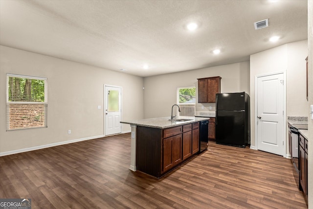 kitchen featuring black appliances, a sink, dark wood finished floors, a kitchen island with sink, and recessed lighting