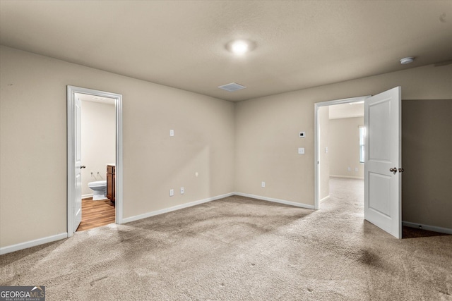 unfurnished bedroom featuring carpet flooring, baseboards, and ensuite bathroom