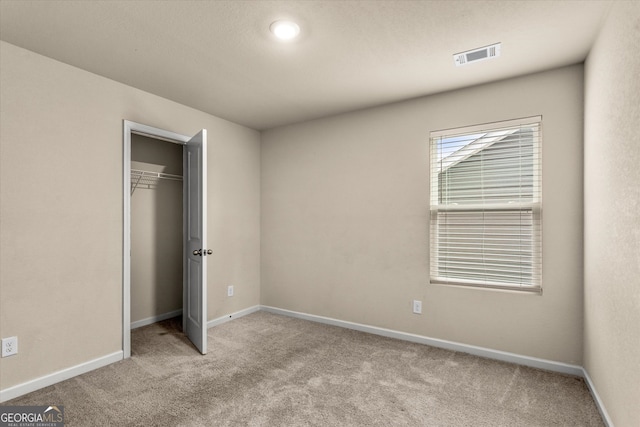 unfurnished bedroom with carpet flooring, baseboards, and a closet