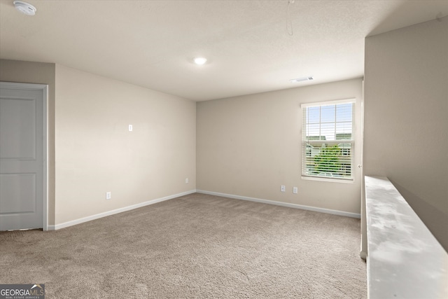 carpeted empty room with baseboards and a smoke detector