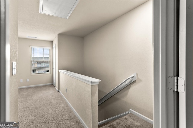 corridor with attic access, an upstairs landing, carpet floors, and baseboards