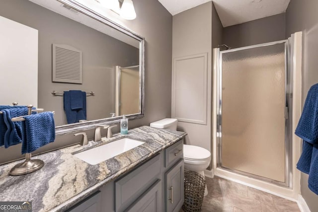 full bath featuring a stall shower, vanity, and toilet