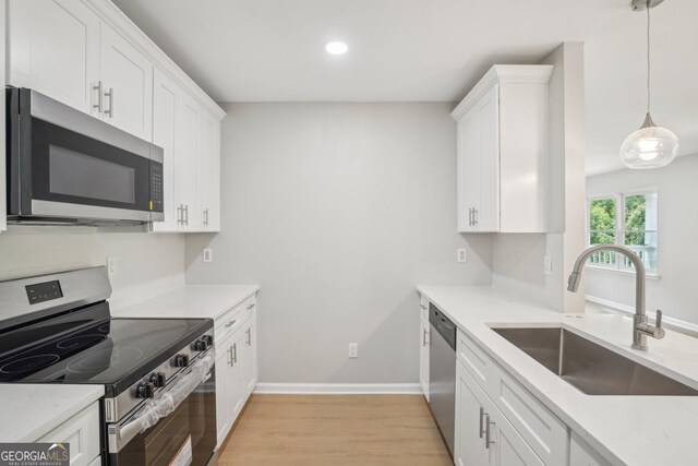 kitchen featuring stainless steel appliances, a sink, light wood-type flooring, white cabinets, and recessed lighting