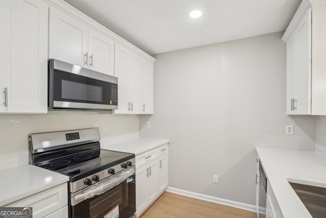kitchen with appliances with stainless steel finishes, light wood-style flooring, baseboards, light countertops, and white cabinets