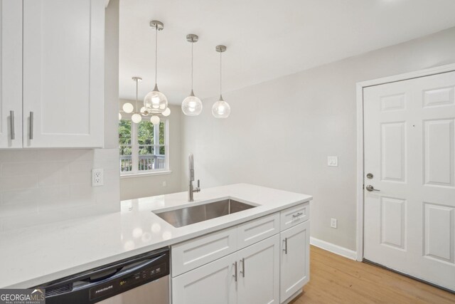 kitchen with a sink, white cabinets, light wood finished floors, stainless steel dishwasher, and light countertops