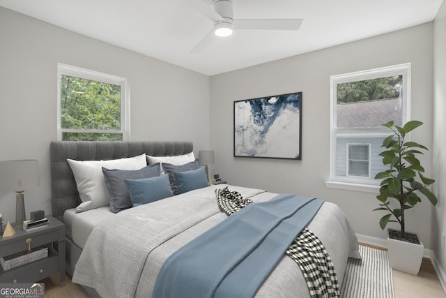 bedroom with light wood finished floors, multiple windows, a ceiling fan, and baseboards