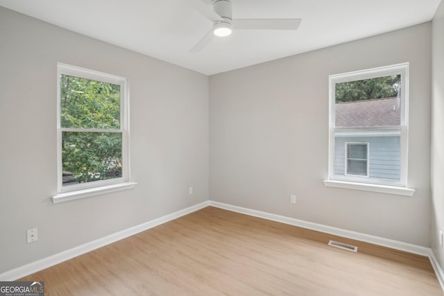 spare room featuring wood finished floors, plenty of natural light, ceiling fan, and baseboards