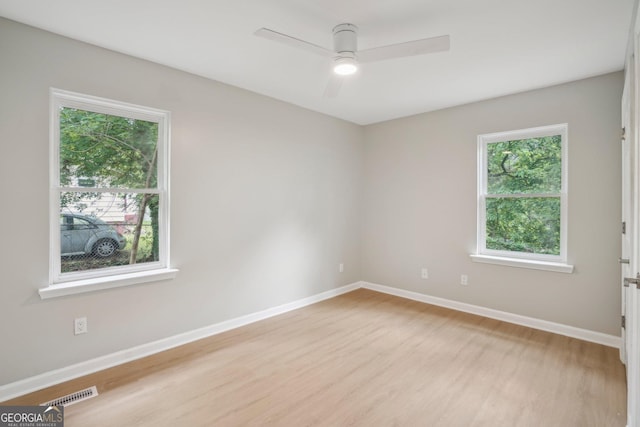 spare room featuring light wood-type flooring, baseboards, and ceiling fan